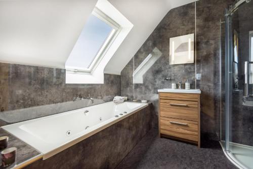 a bathroom with a tub and a sink and a skylight at Tarskavaig Bed & Breakfast in Radernie