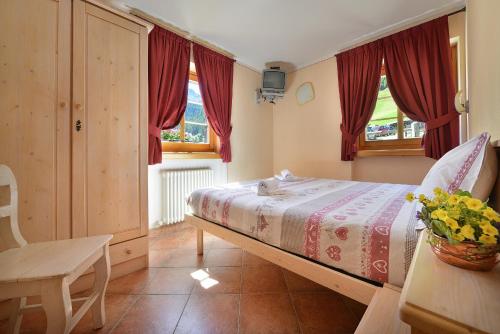 una camera con letto, sedia e finestre di APPARTAMENTI SAN GIOVANNI a Livigno