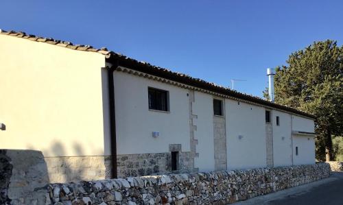 a white building with a stone wall at Borgo delle Stelle in Scicli