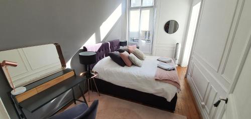 - une chambre avec un lit doté d'oreillers et d'un miroir dans l'établissement L'Ecu : un Haussmannien accueillant!, à Reims