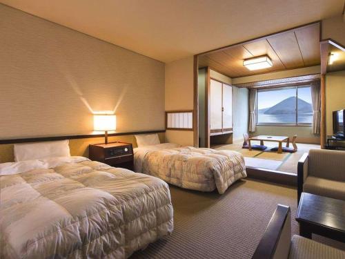 a hotel room with two beds and a large window at Toya Kohan Tei in Lake Toya