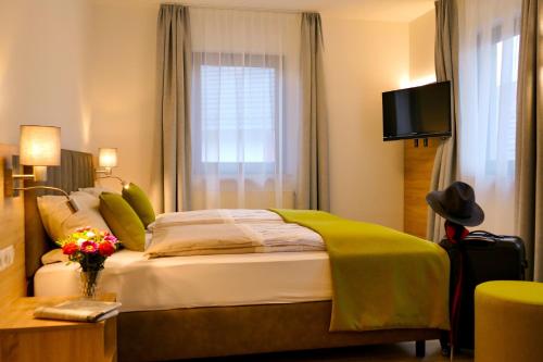 a bedroom with a large bed with a green blanket at Hotel Landgasthof Lell in Künzelsau