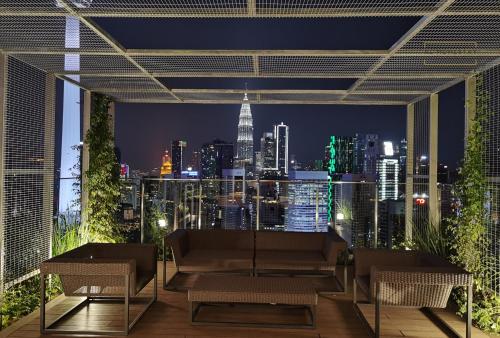 a rooftop patio with a view of the city at night at Ceylonz Suites KL Tower by KL HomeStay in Kuala Lumpur