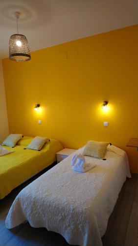 レスパール・メドックにあるCAFE DE PARISの黄色い壁の客室内のベッド2台