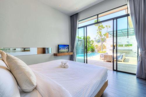 sypialnia z białym łóżkiem i przesuwnymi szklanymi drzwiami w obiekcie Coco Kamala from VillaCarte w mieście Kamala Beach