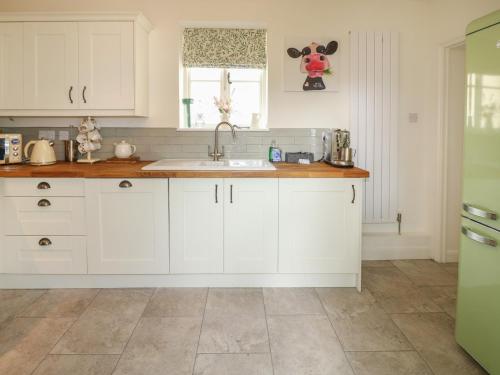 a kitchen with white cabinets and a sink at Holmefield in Bakewell