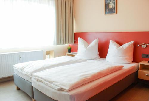 a bedroom with a large bed with a red headboard at PRIMA Inn Ferienwohnungen Sonnenufer am Ruppiner See in Neuruppin