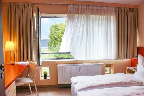 ein Schlafzimmer mit einem Bett und einem großen Fenster in der Unterkunft PRIMA Inn Ferienwohnungen Sonnenufer am Ruppiner See in Neuruppin