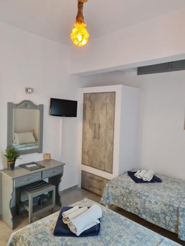 a room with two beds and a desk and a mirror at Zoumis Residence in Naousa