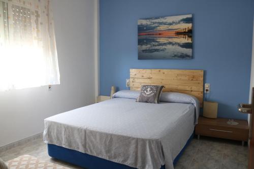 1 dormitorio con 1 cama con pared azul en Apartamento Eucaliptus A - Delta del Ebro, en L'Eucaliptus