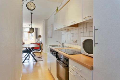 una cucina con mobili bianchi, un lavandino e un microonde di Villa Olga a Blankenberge