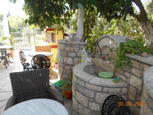 a patio with a table and chairs and a stone fountain at Melios Rooms in Petalidhion