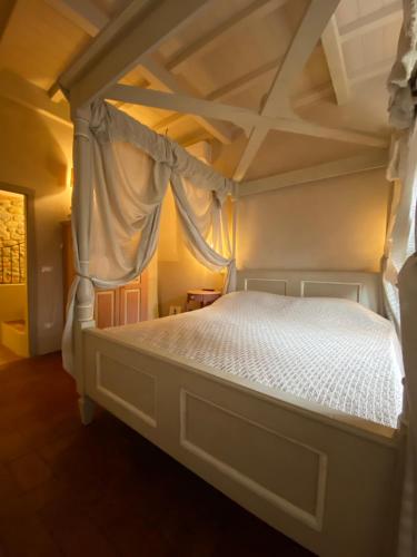 a bedroom with a canopy bed with white sheets at La Magione dei Todaro in Borgo a Buggiano