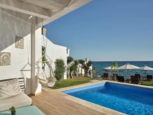 a villa with a swimming pool next to the ocean at Cavo Orient Beach Hotel & Suites in Tragaki