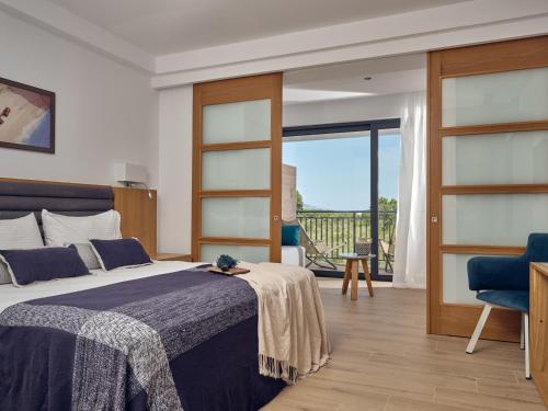 a bedroom with a bed and a view of a balcony at Cavo Orient Beach Hotel & Suites in Tragaki