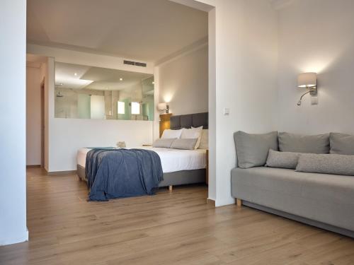 a bedroom with a bed and a couch at Cavo Orient Beach Hotel & Suites in Tragaki