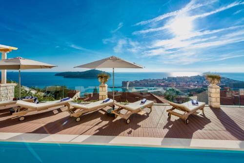 a pool with lounge chairs and umbrellas on a roof at Villa Vega in Dubrovnik