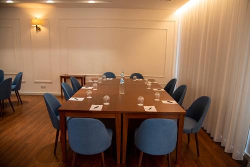 a conference room with a long table and blue chairs at Luna Hotel de Tábua in Tábua