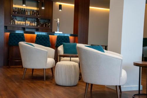 a bar with three white chairs and a counter at Luna Hotel de Tábua in Tábua