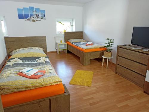 two beds in a room with a tv and a desk at Ubytovanie na Odborárov in Spišská Nová Ves