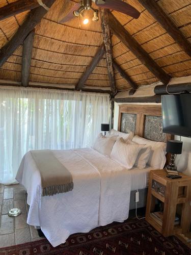 a bedroom with a large white bed with a wooden ceiling at The Place Guesthouse Parys in Parys