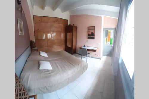 ein Schlafzimmer mit einem großen Bett und einem Schreibtisch in der Unterkunft Loft atelier dans ancien domaine viticole in Moux