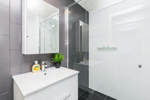 uma casa de banho com um lavatório branco e um chuveiro em KOZYGURU SOUTH BRISBANE FUNKY 1 BED APT FREE PARKING QSB027-1810 em Brisbane