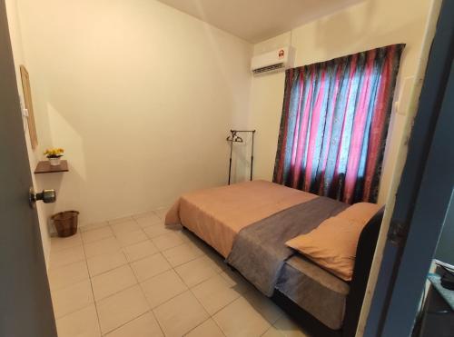 um pequeno quarto com uma cama e uma janela em Homestay at Petrajaya,Kuching em Kuching