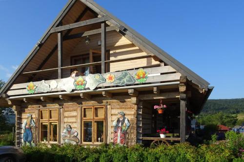 a log cabin with people sitting on the balcony at Chutor Grzegorza in Wysowa-Zdrój