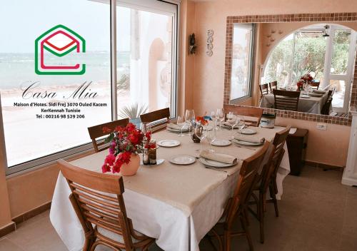 a dining room with a table with chairs and a large window at Casa Mia in Ouled Kacem