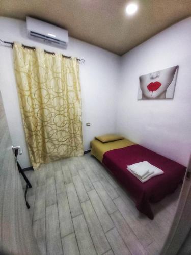 um pequeno quarto com uma cama e uma janela em Acasa viale annunziata messina em Messina