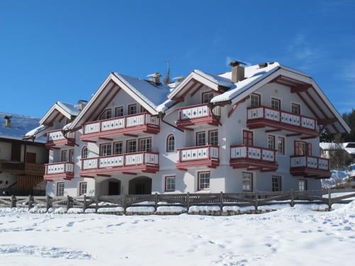 Un grand bâtiment blanc avec de la neige au sol dans l'établissement Casa Azzurra, à Pozza di Fassa