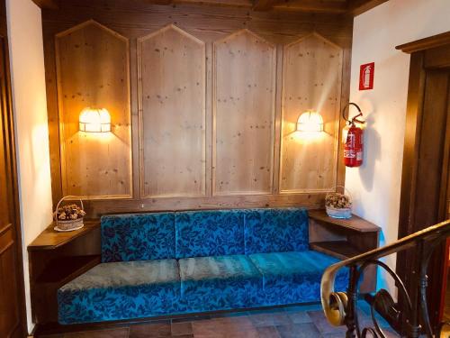 a blue couch in a room with wooden walls at Hotel Molino in Falcade