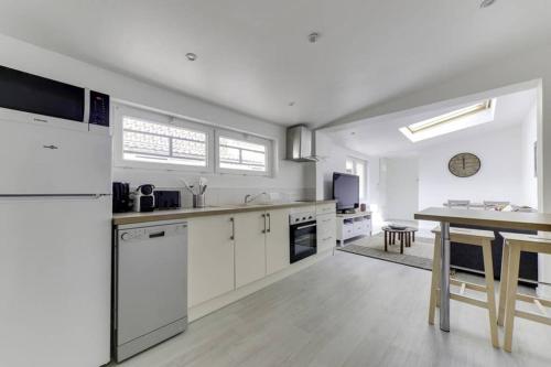 une cuisine avec des armoires blanches et une table à l'intérieur dans l'établissement Natural chic au coeur de Reims, à Reims