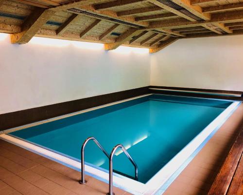 an indoor swimming pool with blue water and wooden ceilings at Hotel Molino in Falcade