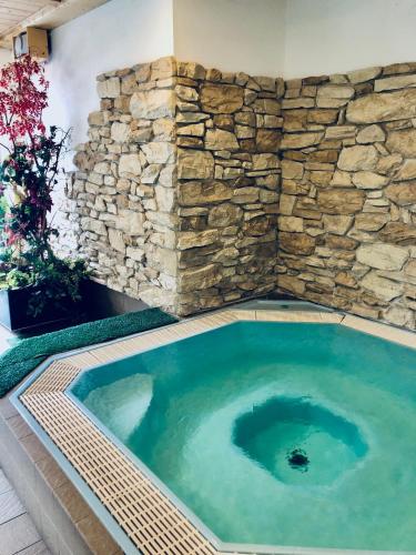 a jacuzzi tub with a stone wall at Hotel Molino in Falcade
