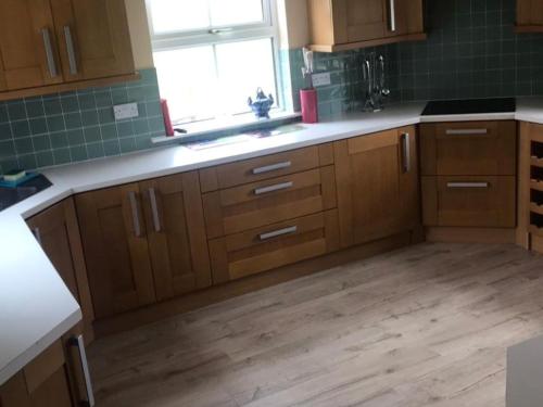 CarsphairnにあるCumnock Knowes Holiday Retreatのウッドフロアのキッチン(木製キャビネット付)