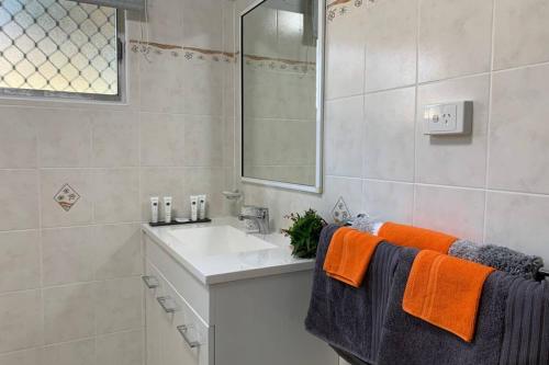 a bathroom with a white sink and orange towels at Andergrove Home with a Garden View-Wi-fi & Netflix in Andergrove