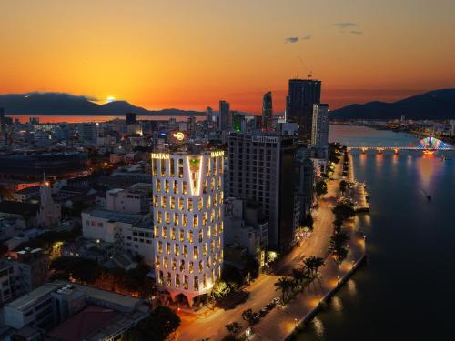 eine Skyline der Stadt bei Sonnenuntergang mit einem hohen Gebäude in der Unterkunft HAIAN Riverfront Hotel Da Nang in Đà Nẵng