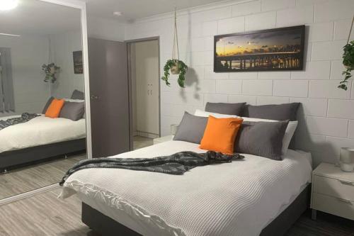 a bedroom with a bed with orange and gray pillows at Andergrove Home with a Garden View-Wi-fi & Netflix in Andergrove