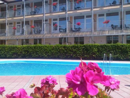 a building with pink flowers in front of a swimming pool at Hotel Ala Bianca in Ameglia