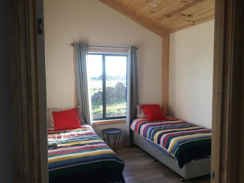 two beds in a room with a window at Meander Country Cabins & Vans in Meander