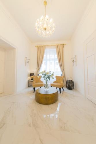 a living room with a table and a chandelier at Palais Gutenberg la Ville in Klagenfurt