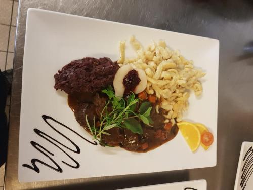 um prato branco de alimentos com arroz e carne em Alemannenhof Hotel Engel em Rickenbach