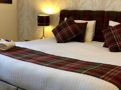 a bed with a plaid blanket and pillows on it at Carisbrooke Guest House in Inverness