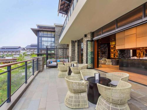 a patio with chairs and tables on a balcony at Pullman Ciawi Vimala Hills Resort in Bogor