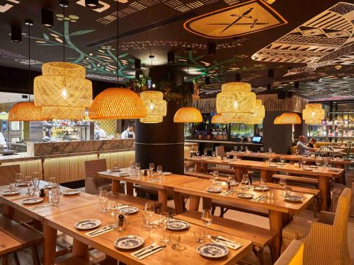 a restaurant with wooden tables and chairs and chandeliers at Mama Shelter London - Shoreditch in London