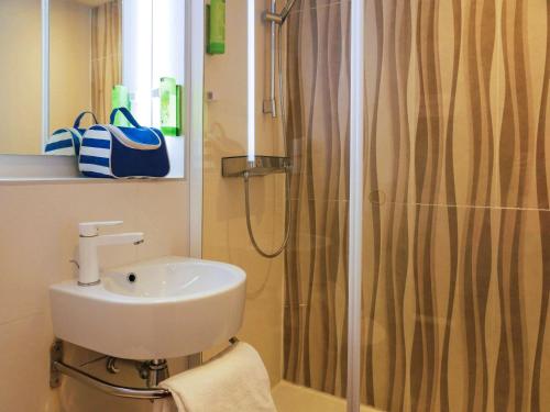 La salle de bains est pourvue d'un lavabo et d'une douche. dans l'établissement greet Hotel Marseille Provence Aéroport, à Vitrolles