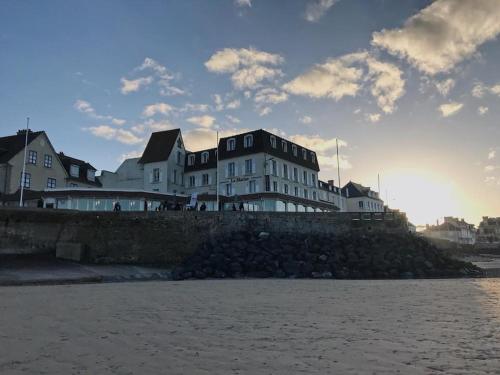 un edificio sentado en la parte superior de una pared junto al agua en Hôtel De La Marine, en Arromanches-les-Bains