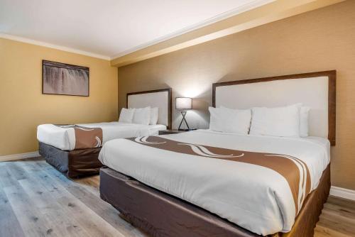 two large beds in a hotel room with yellow walls at Quality Inn & Suites in Niagara Falls
